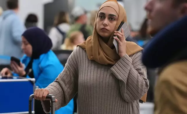 A traveler checks the status of her flight at the O'Hare International Airport in Chicago, Sunday, Nov. 30, 2025. (AP Photo/Nam Y. Huh)