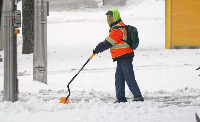 A person shovels a sidewalk after a winter snow storm in Pottsville, Pa., Tuesday, Dec. 2, 2025. (AP Photo/Matt Rourke)