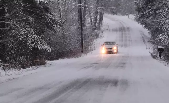 A car rolls down a snow covered road during a winter storm, Tuesday, Dec. 2, 2025, in East Derry, N.H. (AP Photo/Charles Krupa)