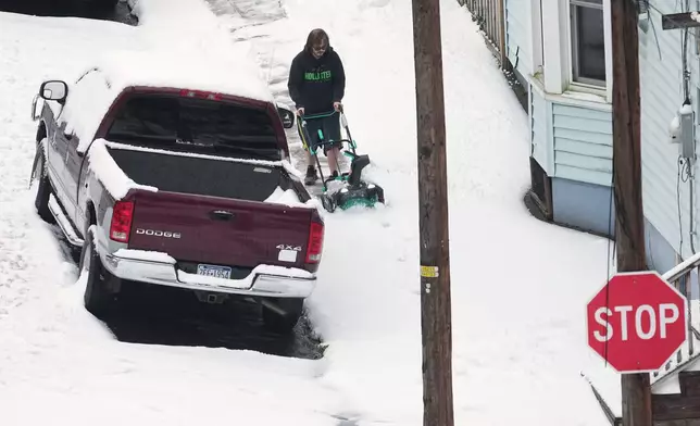 A person clears a sidewalk after a winter snow storm in Pottsville, Pa., Tuesday, Dec. 2, 2025. (AP Photo/Matt Rourke)