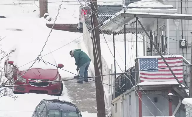 A person shovels a sidewalk after a winter snow storm in Pottsville, Pa., Tuesday, Dec. 2, 2025. (AP Photo/Matt Rourke)