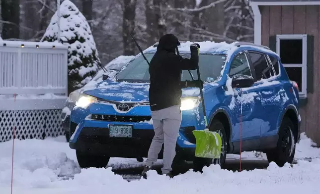 A man clears snow from his car during a winter storm, Tuesday, Dec. 2, 2025, in Salem, N.H. (AP Photo/Charles Krupa)