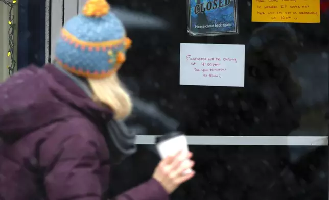 A person walks past a business that closed due to snow in Portsmouth, N.H., Tuesday, Dec. 2, 2025. (AP Photo/Caleb Jones)