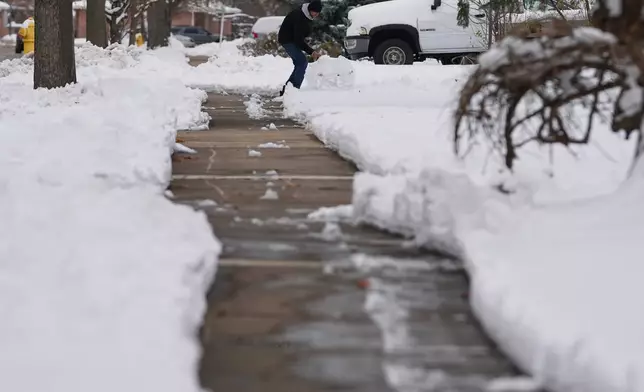 A person cleans snow in Glenview, Ill., Monday, Dec. 1, 2025. (AP Photo/Nam Y. Huh)
