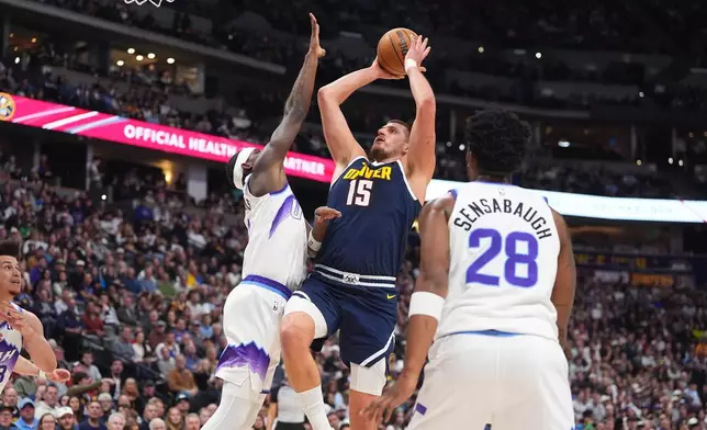 Denver Nuggets center Nikola Jokić, center, drives to the rim between Utah Jazz forwards Taylor Hendricks, left, and Brice Sensabaugh in the first half of an NBA basketball game Monday, Dec. 22, 2025, in Denver. (AP Photo/David Zalubowski)