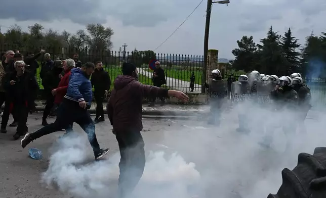 A man kicks a tear gas canister back toward riot police during clashes after farmers tried to block the main access road to Thessaloniki's international airport, northern Greece, on Friday, Dec. 5, 2025, as protests over delays in European Union-backed agricultural subsidy payments escalated. (AP Photo/Giannis Papanikos)