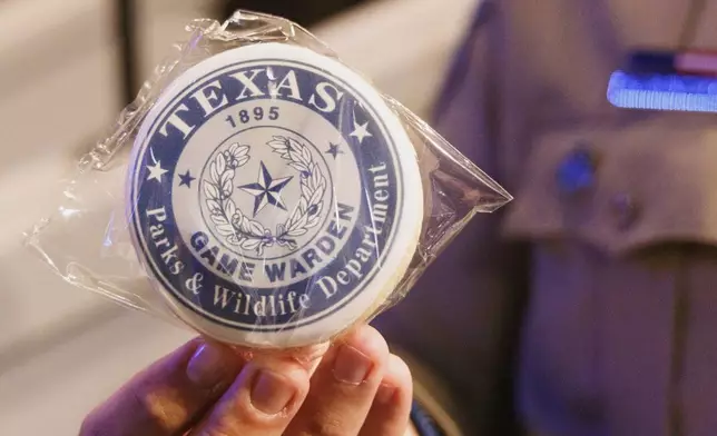 In this photo provided by the Texas Parks and Wildlife Department a person holds up a game warden badge during the 67th Texas Game Warden and State Park Police Officer Commissioning Ceremony on May 30, 2025, in Austin, Texas. (Sonja Sommerfeld/Texas Parks and Wildlife Department via AP)