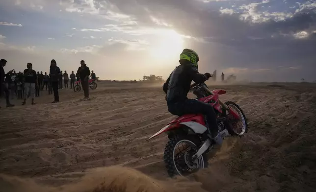 Palestinian Ahmed Abu Amra, 23, rides his motorcycle and shows off his skills on a sandy hill in the Al-Zahra area, central Gaza Strip, Friday, Dec. 5, 2025. (AP Photo/Abdel Kareem Hana)