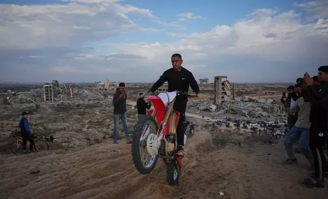 A Palestinian man rides his motorcycle on a sand dune in the Al-Zahra area, in the central Gaza Strip, Friday, Dec. 5, 2025. (AP Photo/Abdel Kareem Hana)