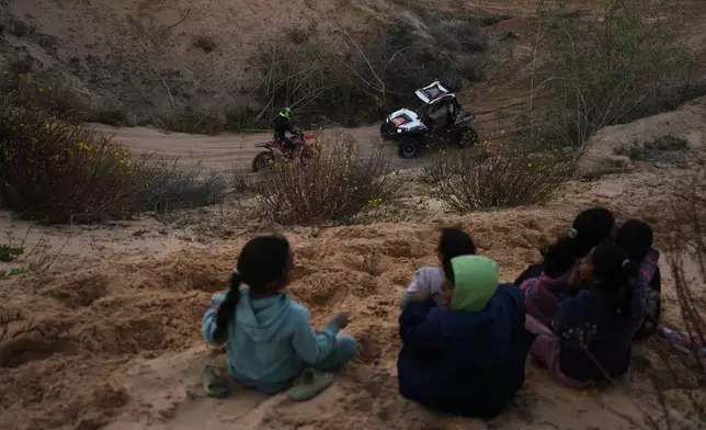 Palestinians watch youths riding their motorcycles and ATV on sand dunes in the Al-Zahra area, in the central Gaza Strip, Friday, Dec. 5, 2025. (AP Photo/Abdel Kareem Hana)