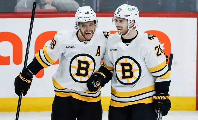Boston Bruins' David Pastrnak (88) and Elias Lindholm (28) celebrate Lindholm's goal against the Winnipeg Jets during the third period of an NHL hockey game, in Winnipeg, Manitoba, Thursday, Dec. 11, 2025. (John Woods/The Canadian Press via AP)