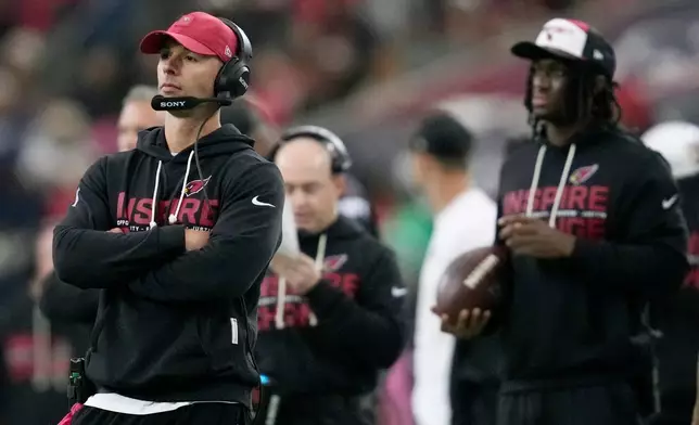 Arizona Cardinals head coach Jonathan Gannon, left, and injured Cardinals wide receiver Marvin Harrison Jr. watch the action on the field during the first half of an NFL football game against the Houston Texans Sunday, Dec. 14, 2025, in Houston. (AP Photo/Ashley Landis)