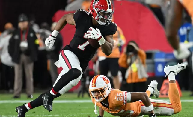 Atlanta Falcons running back Bijan Robinson (7) runs against Tampa Bay Buccaneers cornerback Jacob Parrish (25) during the first half of an NFL football game, Thursday, Dec. 11, 2025, in Tampa, Fla. (AP Photo/Jason Behnken)