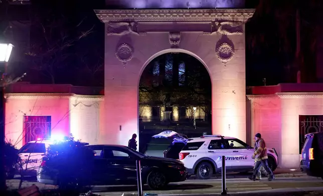 Police gather outside an entrance to Brown University in Providence, R.I., on Saturday, Dec. 13, 2025, during the investigation of a shooting. (AP Photo/Mark Stockwell)