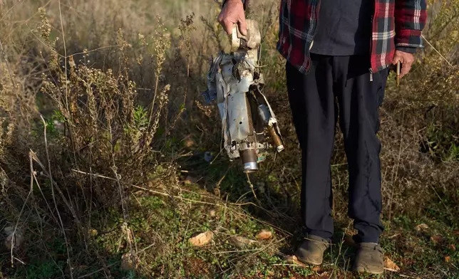 Ilan Rosenfeld holds a piece of a rocket fired by Hezbollah in his burnt-out business in Israel's northernmost town of Metula, Sunday, Nov. 30, 2025. (AP Photo/Ariel Schalit)