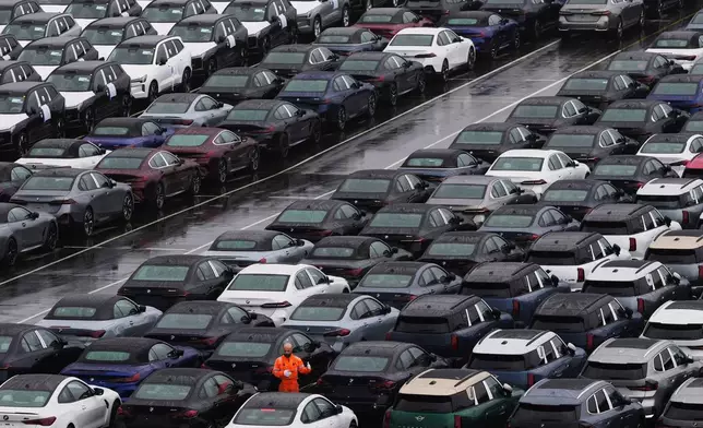 FILE - A worker checks on new cars parked in a lot at the International Car Operators terminal in the Port of Zeebrugge, Belgium, July 31, 2025. (AP Photo/Virginia Mayo, File)