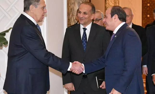 In this photo, provided by Egypt's presidency media office, Egyptian President Abdel-Fattah el-Sissi, front right, greets Russian Foreign Minister Sergey Lavrov, left, before their meeting at the Presidential Palace in Cairo, Egypt, Saturday, Dec. 20, 2025. (Egyptian Presidency Media Office via AP)