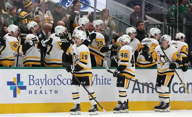 Pittsburgh Penguins center Connor Dewar (19) is congratulated by teammates on his bench after scoring a goal against the Dallas Stars during the first period of an NHL hockey game Sunday, Dec. 7, 2025, in Dallas. (AP Photo/Sam Hodde)
