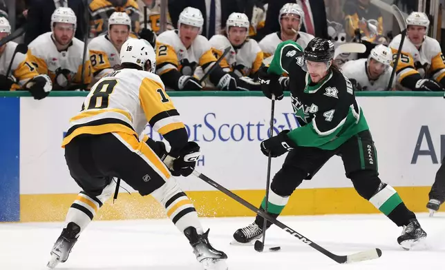 Dallas Stars defenseman Miro Heiskanen (4) is defended by Pittsburgh Penguins center Tommy Novak (18) during the first period of an NHL hockey game Sunday, Dec. 7, 2025, in Dallas. (AP Photo/Sam Hodde)