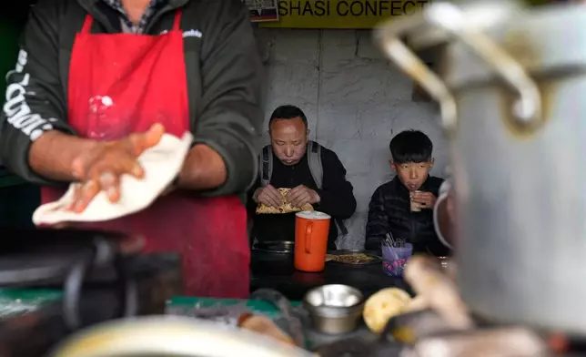 Sonam Tashi and his son, Kunga Tenzin, eat breakfast at a roadside stall in Mcleodganj near Dharamshala, India, March 7, 2025. (AP Photo/Manish Swarup)