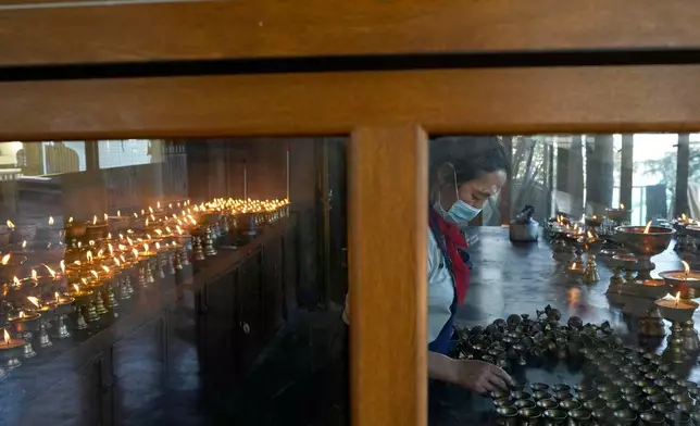 A Tibetan nun cleans copper lamps at Tsuglakhang temple in Mcleodganj near Dharamshala, India, March 6, 2025. (AP Photo/Manish Swarup)