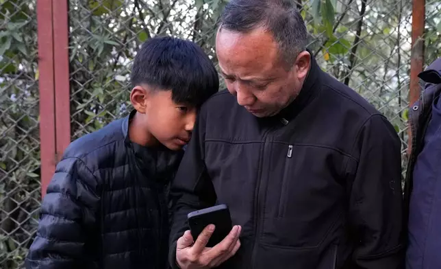 Sonam Tashi, right, and his son, Kunga Tenzin, wait for transportation for Mcleodganj after reaching Dharamshala, India, where Tashi hopes the Tibetan government in exile can help his son access education, March 5, 2025. (AP Photo/Manish Swarup)