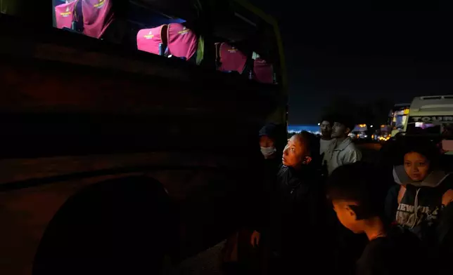 Sonam Tashi and his son, Kunga Tenzin, bottom right, prepare to board their bus to Dharamshala in New Delhi, India, March 5, 2025. (AP Photo/Manish Swarup)