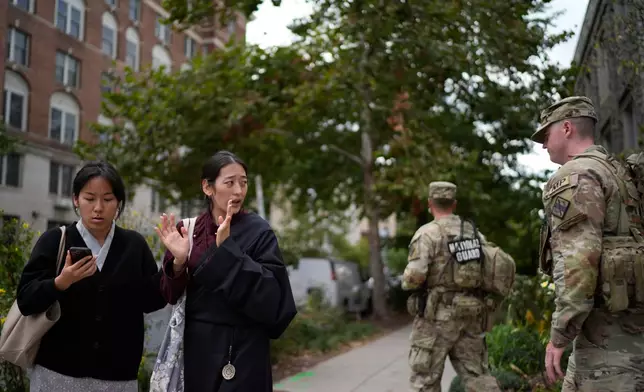Namkyi, right, a Tibetan former political prisoner who was arrested at 15 for protesting Chinese rule, walks past National Guard troops on patrol with Tsejin Khando, with the International Campaign for Tibet, to a meeting, Oct. 7, 2025, in Washington. (AP Photo/David Goldman)