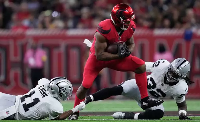 Houston Texans running back Nick Chubb, middle, runs against Las Vegas Raiders safety Jeremy Chinn (11) and safety Lonnie Johnson Jr. during the second half of an NFL football game, Sunday, Dec. 21, 2025, in Houston. (AP Photo/Ashley Landis)