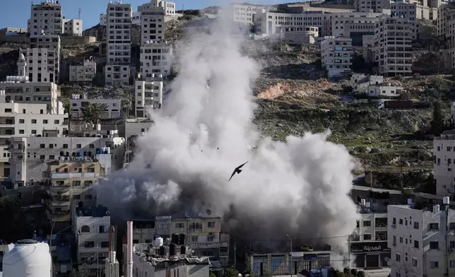 Smoke rises as Israeli forces demolish the home of Abdul Karim Sanoubar, a suspected Palestinian militant who has been accused by Israel of planting bombs on buses in central Israel, in Nablus, West Bank, Tuesday, Dec. 2, 2025. (AP Photo/Majdi Mohammed)