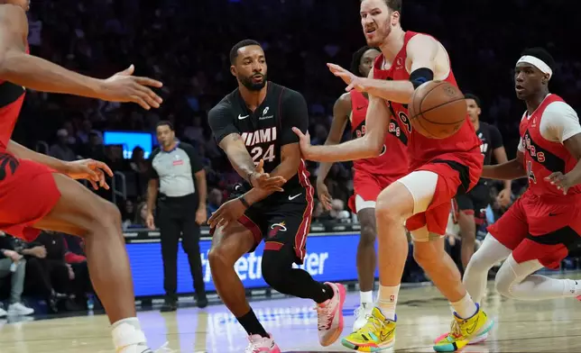 Miami Heat guard Norman Powell (24) passes the ball as Toronto Raptors forward RJ Barrett (9) defends during the first half of an NBA basketball game, Monday, Dec. 15, 2025, in Miami. (AP Photo/Lynne Sladky)