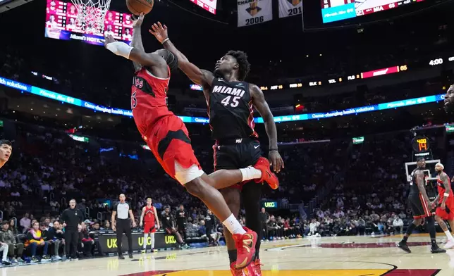 Toronto Raptors guard Jamal Shead, left, goes to the basket as Miami Heat guard Davion Mitchell (45) defends during the second half of an NBA basketball game, Monday, Dec. 15, 2025, in Miami. (AP Photo/Lynne Sladky)