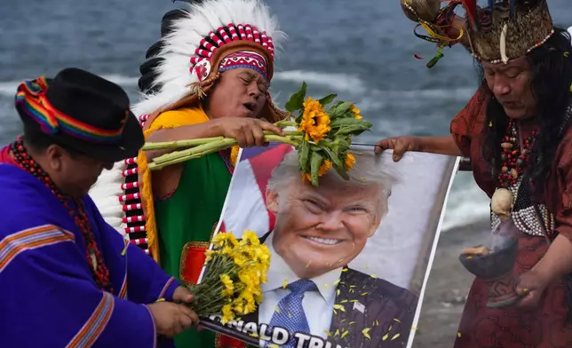 Shamans hold a photo of U.S. President Donald Trump during an annual ritual to predict political and social issues for the new year in Lima, Peru, Monday, Dec. 29, 2025. (AP Photo/Guadalupe Pardo)