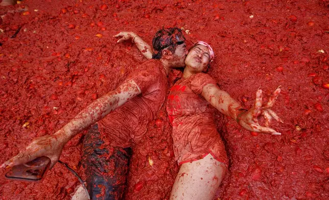A couple kisses over a puddle of tomatoes during the annual "Tomatina" tomato fight fiesta, in the village of Bunol near Valencia, Spain, Aug. 27, 2025. (AP Photo/Alberto Saiz, File)