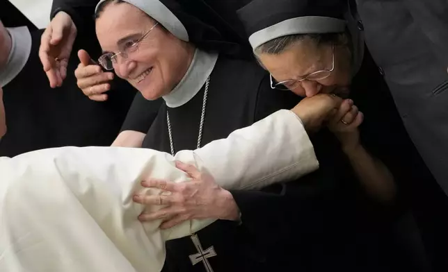 A nun kisses the hand of Pope Leo XIV during his weekly general audience, at The Vatican, Aug.20, 2025. (AP Photo/Gregorio Borgia, File)