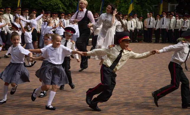 Schoolgirls and cadets dance as they attend a rehearsal of a ceremony on the first day at school at a cadet lyceum in Kyiv, Sept. 1, 2025. (AP Photo/Efrem Lukatsky, File)