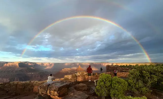 People gather at an overlook as a double rainbow appears over Dead Horse Point State Park, near Moab, Utah, after sunrise, following a thunderstorm, Oct. 9, 2025. (AP Photo/Becky Bohrer, File)