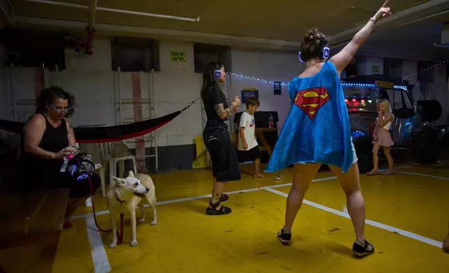 People dance during a headphones party inside an underground parking lot used as a shelter against potential missile strikes from Iran, in Tel Aviv, Israel, June 23, 2025. (AP Photo/Oded Balilty, File)