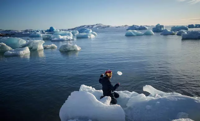 A boy throws ice into the sea in Nuuk, Greenland, March 11, 2025. (AP Photo/Evgeniy Maloletka, File)