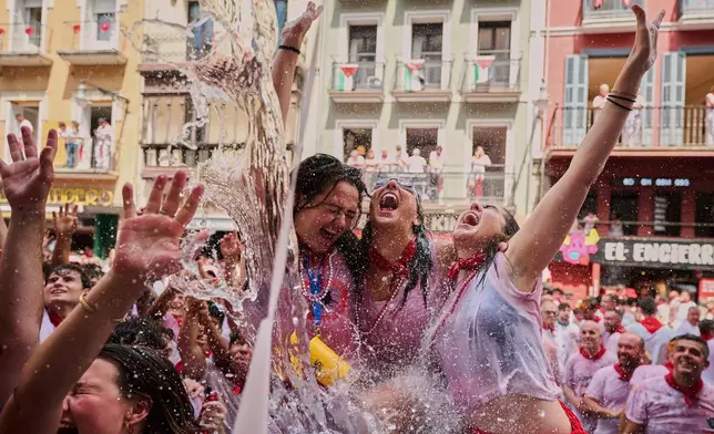 Revelers cool off with water thrown from balconies at the start of nine days of uninterrupted partying during the famed running of the bulls festival in Pamplona, Spain, July 6, 2025. (AP Photo/Miguel Oses, File)