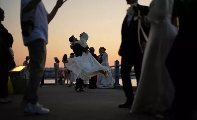 A couple wearing wedding attire dance during a photo session at the Galata Bridge in Istanbul, Turkey, June 13, 2025. (AP Photo/Francisco Seco, File)