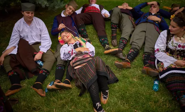 Members of a traditional group from Serbia rest in the shade before a parade by international ensembles and those of ethnic groups from Romania showcasing traditional outfits, dances, and songs, in Bucharest, Romania, June 21, 2025. (AP Photo/Vadim Ghirda, File)