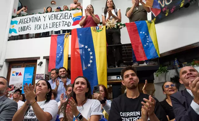 People applaud while watching the ceremony of the Nobel Peace Prize for Venezuelan opposition leader Maria Corina Machado in Norway, during a live viewing in Buenos Aires, Argentina, Wednesday, Dec. 10, 2025. (AP Photo/Rodrigo Abd)