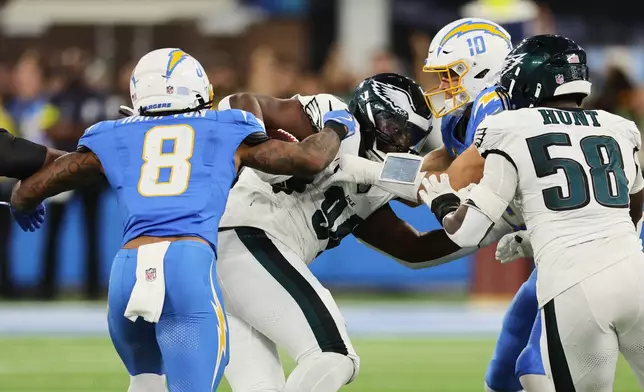Philadelphia Eagles defensive tackle Byron Young (94) recovers a fumble by Los Angeles Chargers quarterback Justin Herbert (10) during the first half of an NFL football game Monday, Dec. 8, 2025, in Inglewood, Calif. (AP Photo/Kevork Djansezian)