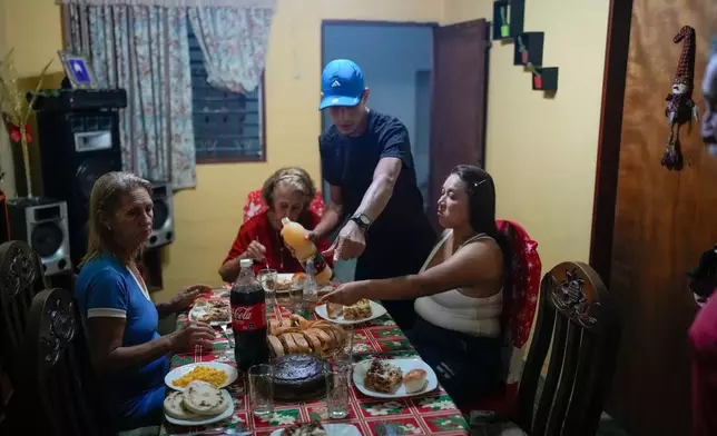 Mariela Gómez, right, and her partner Abraham Castro, a Venezuelan migrant couple, sit for Christmas dinner at Castro's parents' home in Maracay, Venezuela, early Thursday, Dec. 25, 2025. The couple abandoned their journey to the United States and returned home from Mexico by land and sea following President Donald Trump's immigration crackdown. (AP Photo/Matias Delacroix)