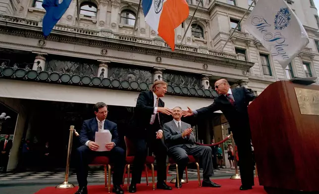 FILE - Donald Trump, second from left and former owner of the Plaza Hotel, reaches to shake the hand of Robert Small, right, CEO of Fairmont Hotel Management at a flag raising ceremony at the Plaza Hotel, July 28, 1995. (AP Photo/Adam Nadel, File)