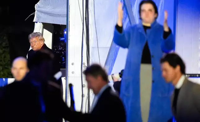 An American Sign Language interpreter, right, signs as President Donald Trump arrives for the lighting of the National Christmas Tree on the Ellipse, Thursday, Dec. 4, 2025, near the White House in Washington. (AP Photo/Julia Demaree Nikhinson)