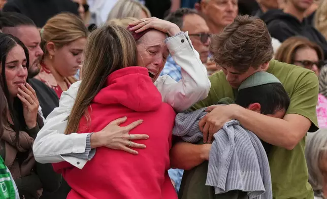 A family reacts during a menorah lighting ceremony at a floral memorial for victims of Sunday's shooting, at the Bondi Pavilion on Bondi Beach on Tuesday, Dec. 16, 2025, in Sydney, Australia. (AP Photo/Mark Baker)