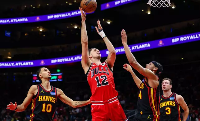 Chicago Bulls forward Zach Collins (12) shoots over Atlanta Hawks forward Asa Newell, right, during the first half of an NBA basketball game, Sunday, Dec. 21, 2025, in Atlanta. (AP Photo/Colin Hubbard)