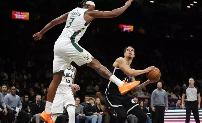 Brooklyn Nets forward Michael Porter Jr. gets Milwaukee Bucks center Myles Turner (3) up in the air while he drives to the basket during the first half of an NBA basketball game, Sunday, Dec. 14, 2025, in New York. (AP Photo/Heather Khalifa)